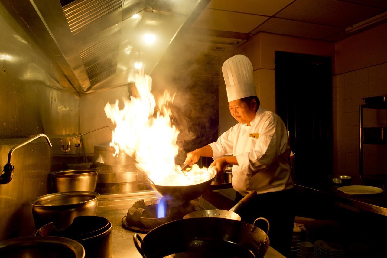 Thistle Port Dickson Resort Buitenkant foto A chef cooking with a wok